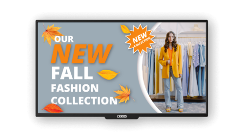 Digital display on a kiosk screen showcasing a woman in a yellow jacket as part of the New Fall Fashion Collection at a clothing store, highlighted by autumn-themed decorations.