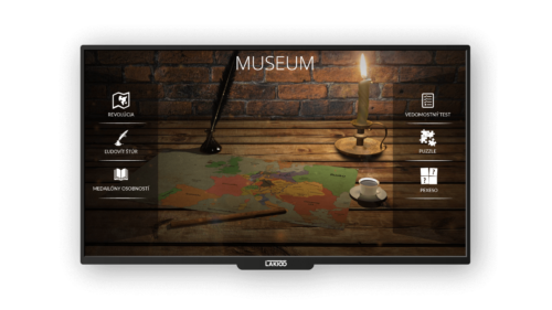 nteractive digital display in a museum setting, featuring a rustic table with a map, candle, quill, and coffee, against a brick wall, with menu options for historical exploration and games.